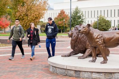 Students walking past pride statues