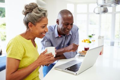 mature couple drinking coffee together at laptop