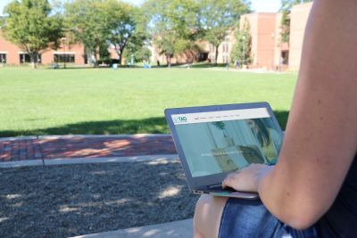Person outdoors at Memorial Field on a laptop open to TAO Connect website