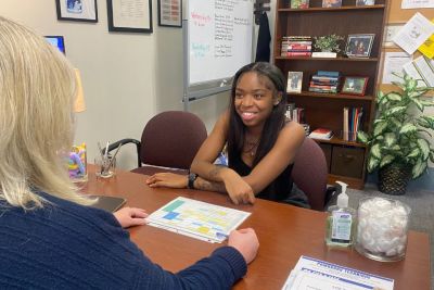 A female student sits at a desk with her academic coach.