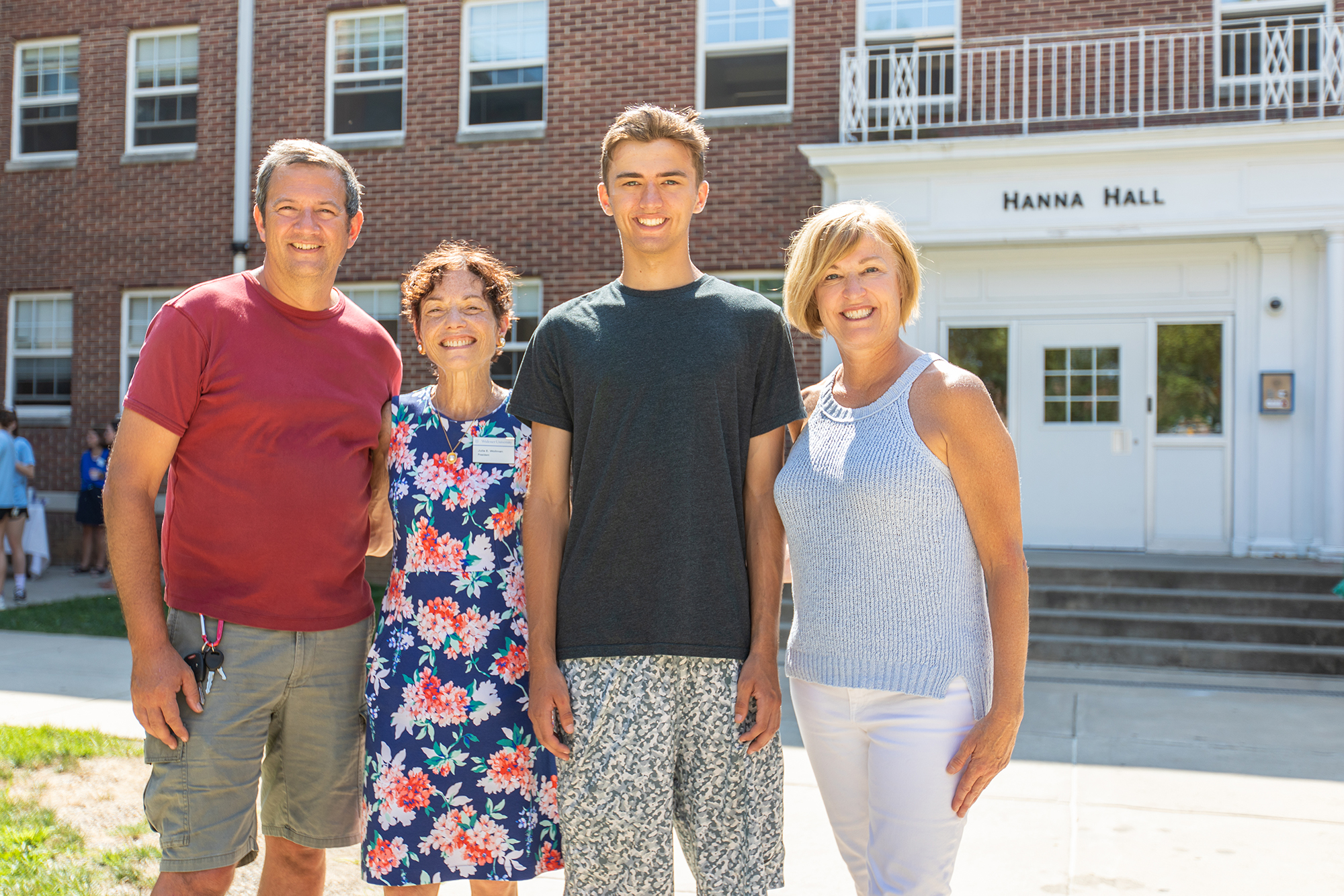 Carson Slook, a fourth-generation Widener student, poses with his parents and President Wollman in front of Hanna Hall, named for his great-grandfather
