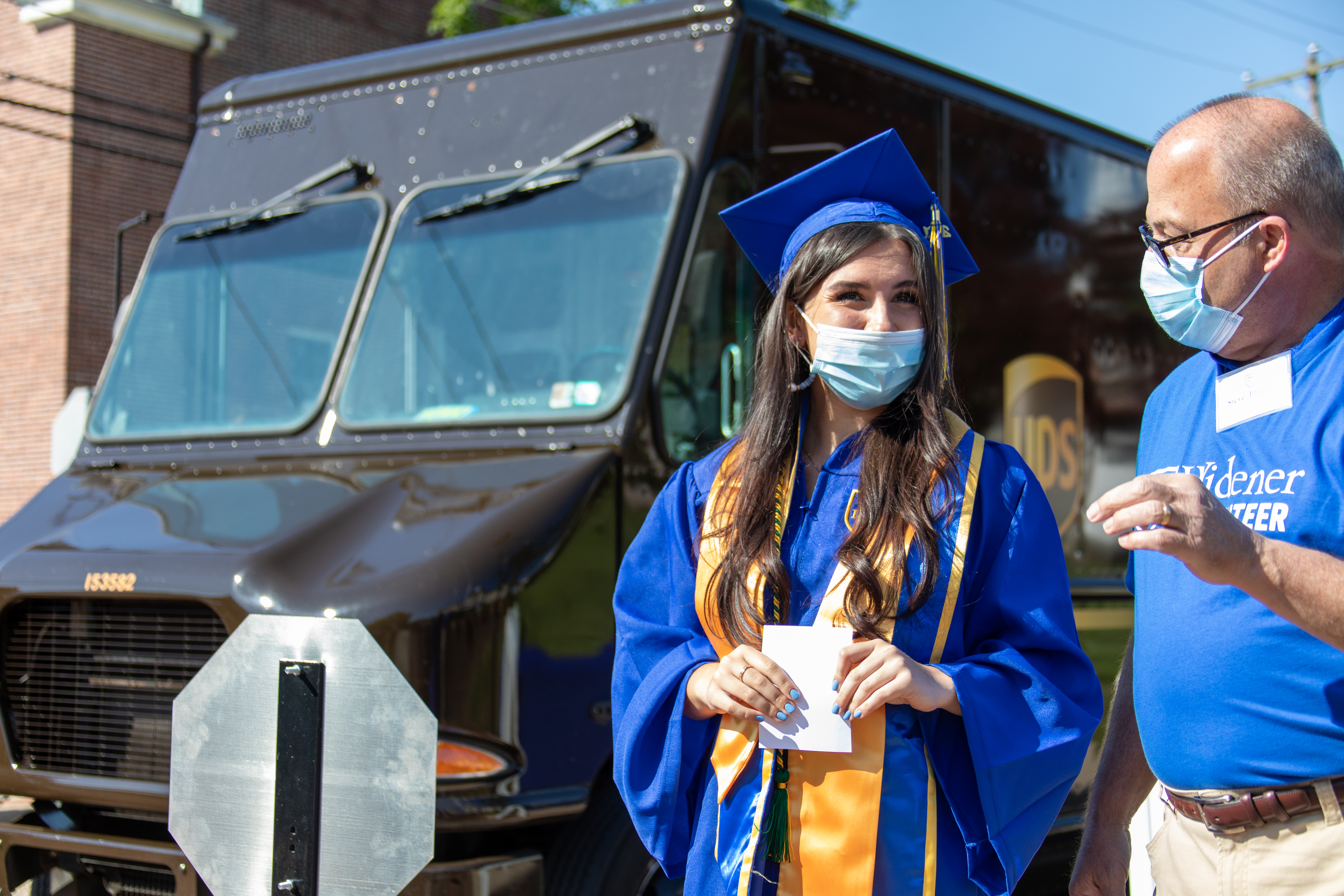Graduate talks to staff member in front of UPS delivery truck