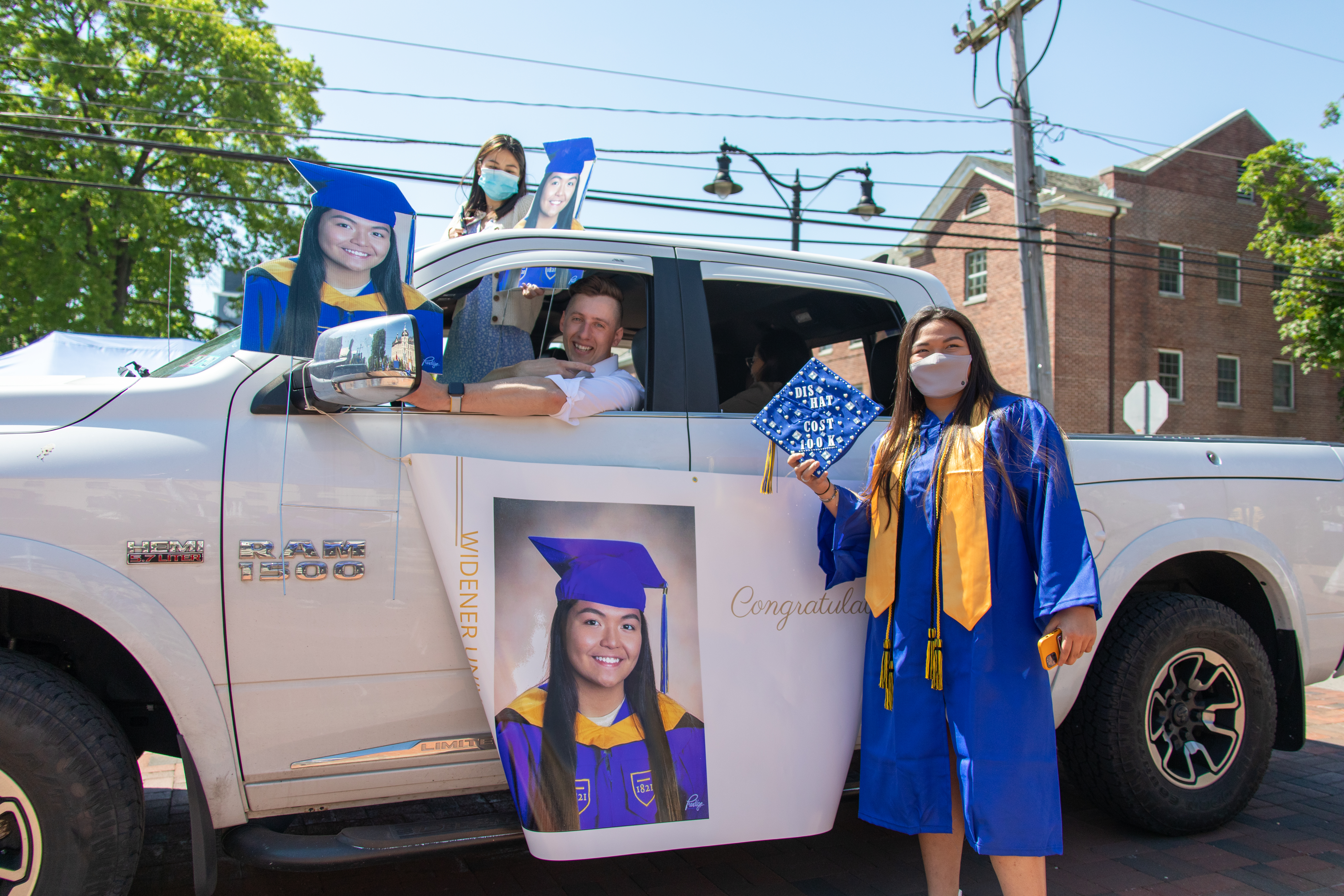 Graduate stands in front of white truck decorated with pictures of herself