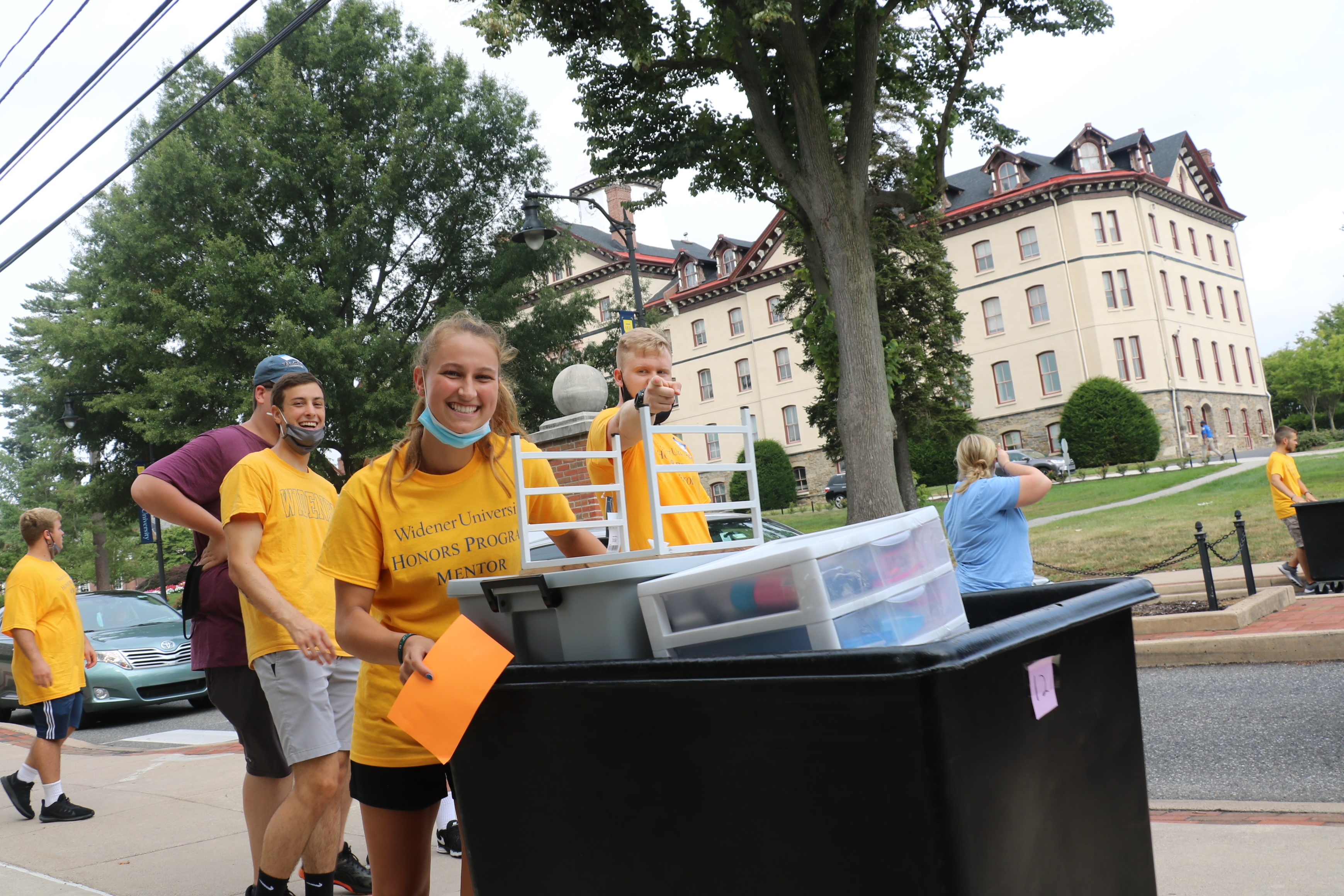 Three volunteer students smile while working at move-in day