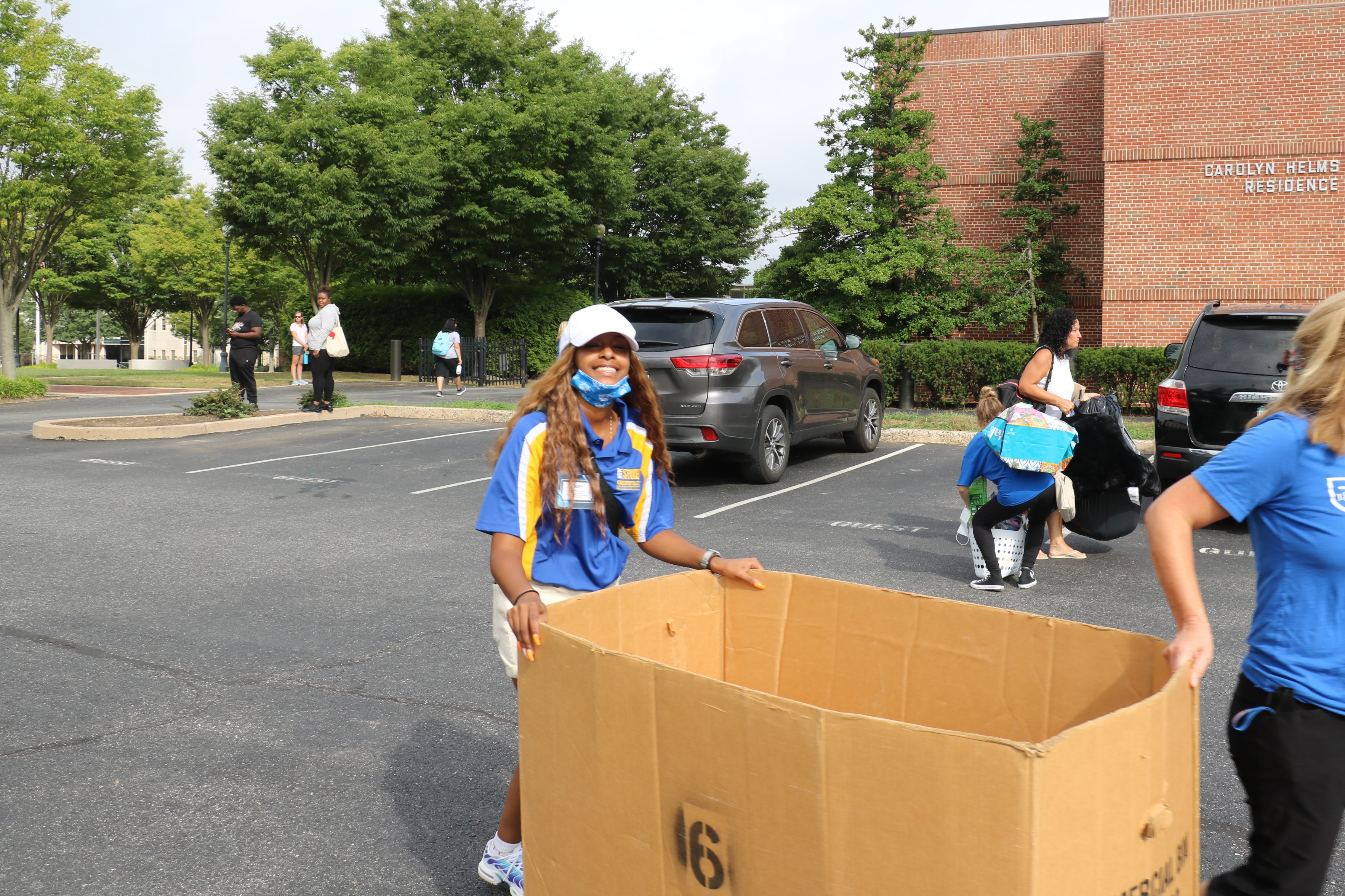 A female student volunteer smiles while pushing a bin