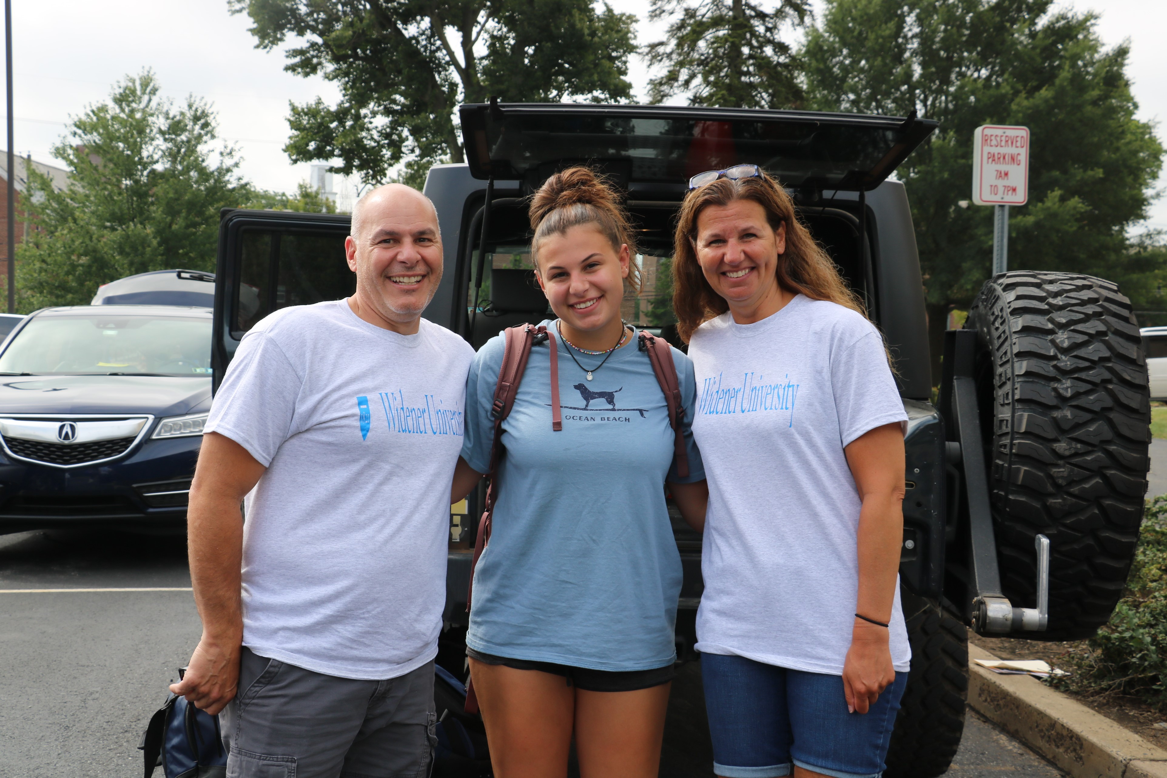 A female student poses with her parents at move-in day