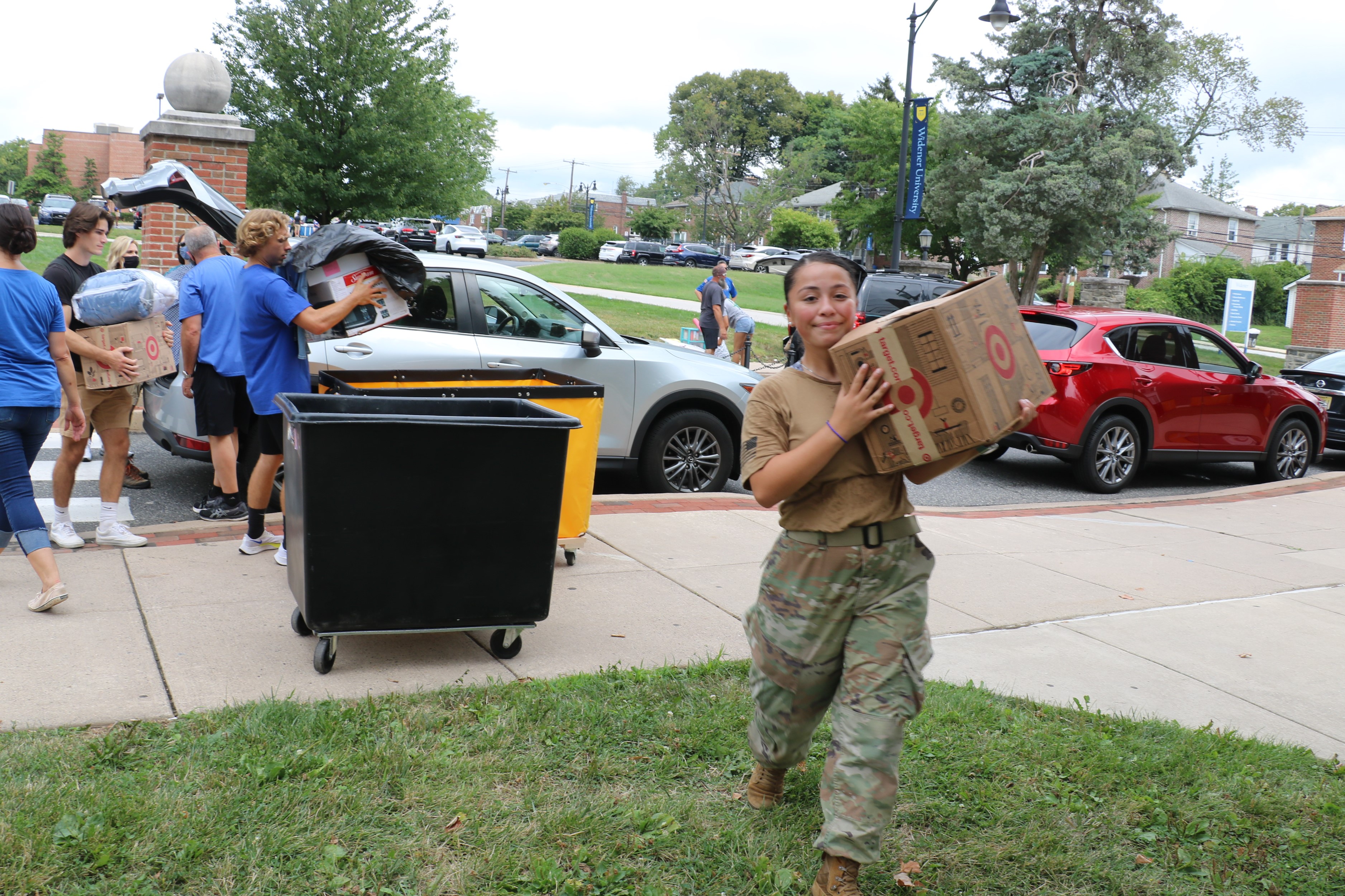 A female ROTC cadet carries luggage for an incoming student