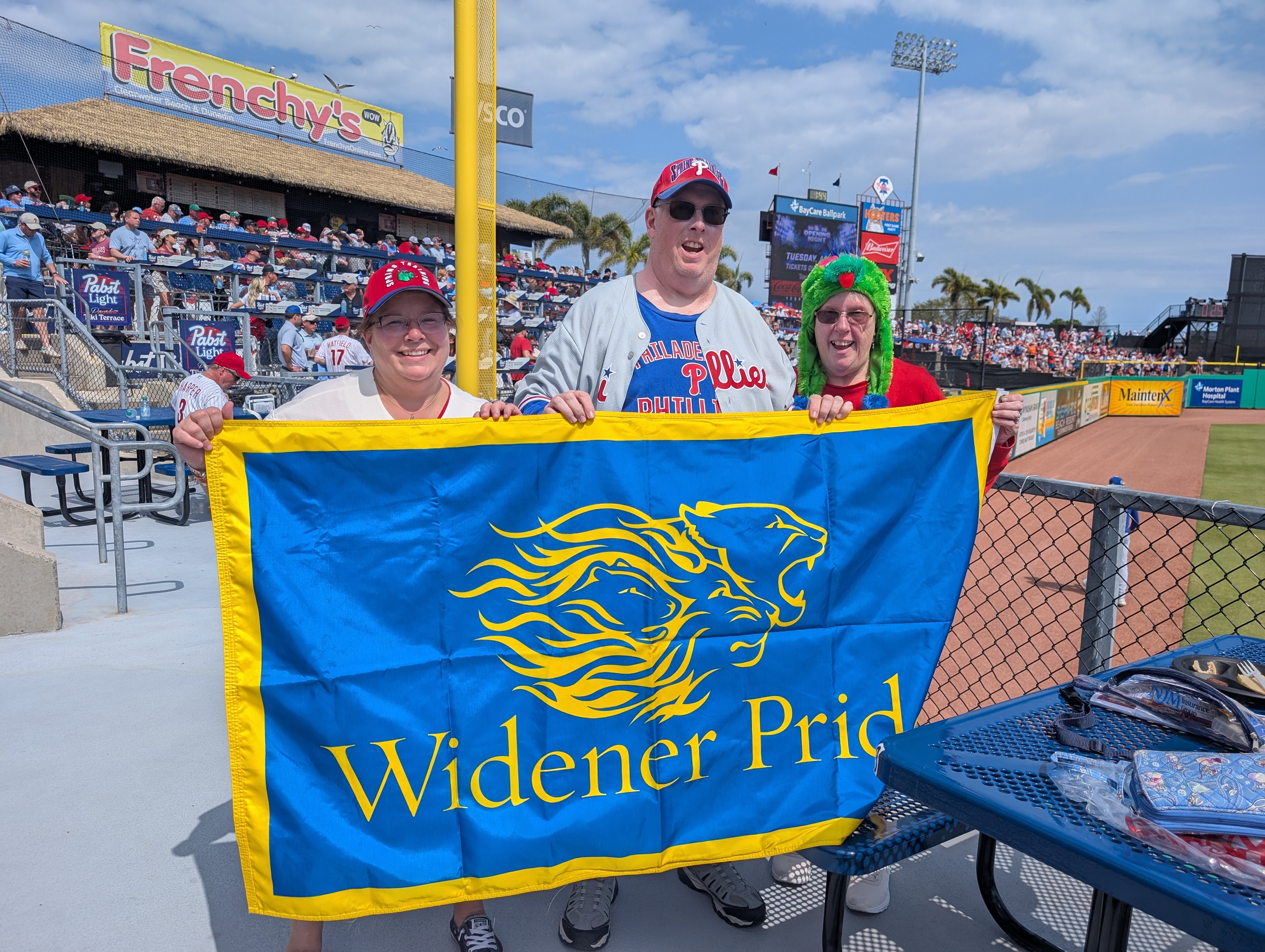 Alumni hold a Widener Pride flag