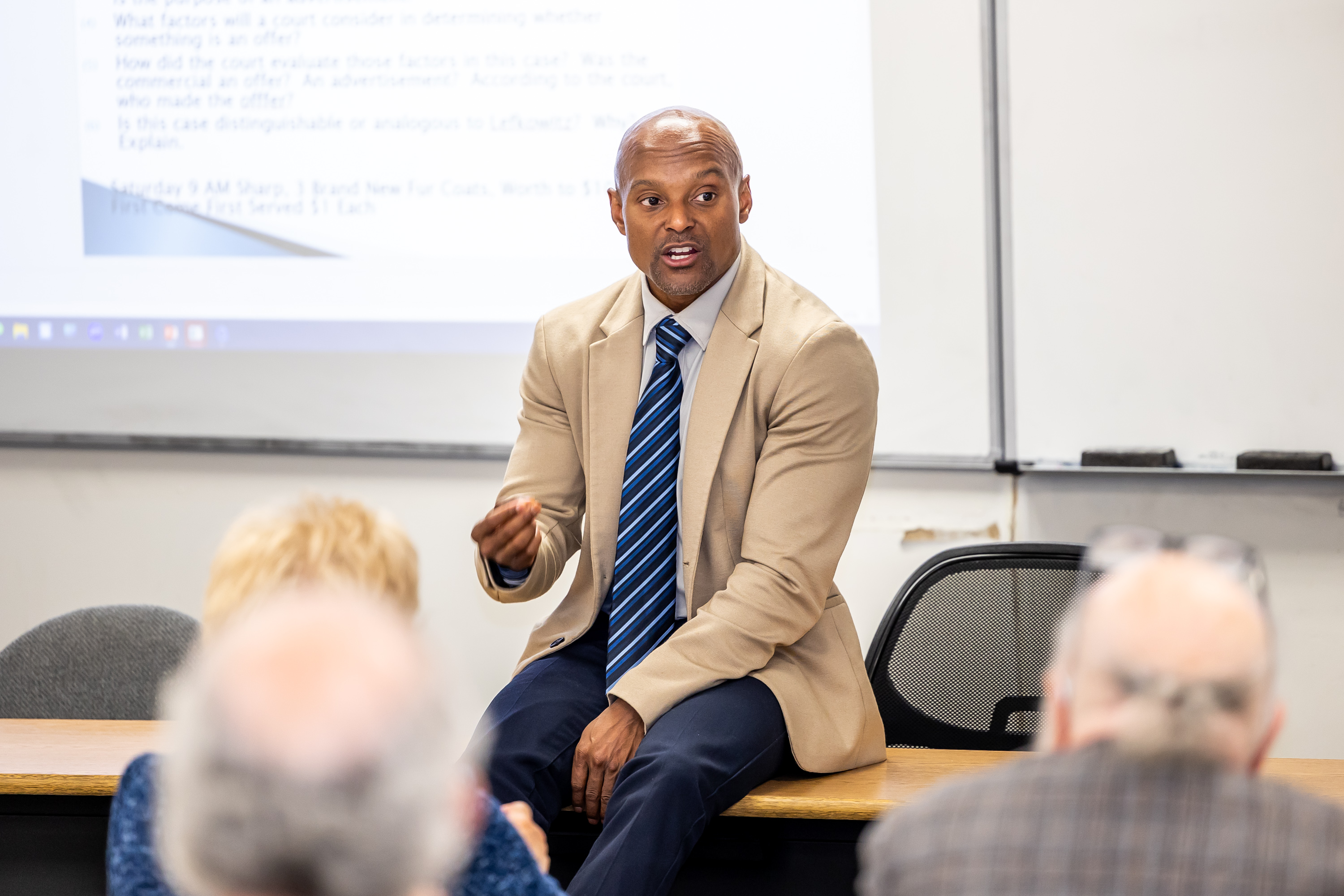 Dean Todd Clark sits on a desk during a simulated "back to class" reunion event.