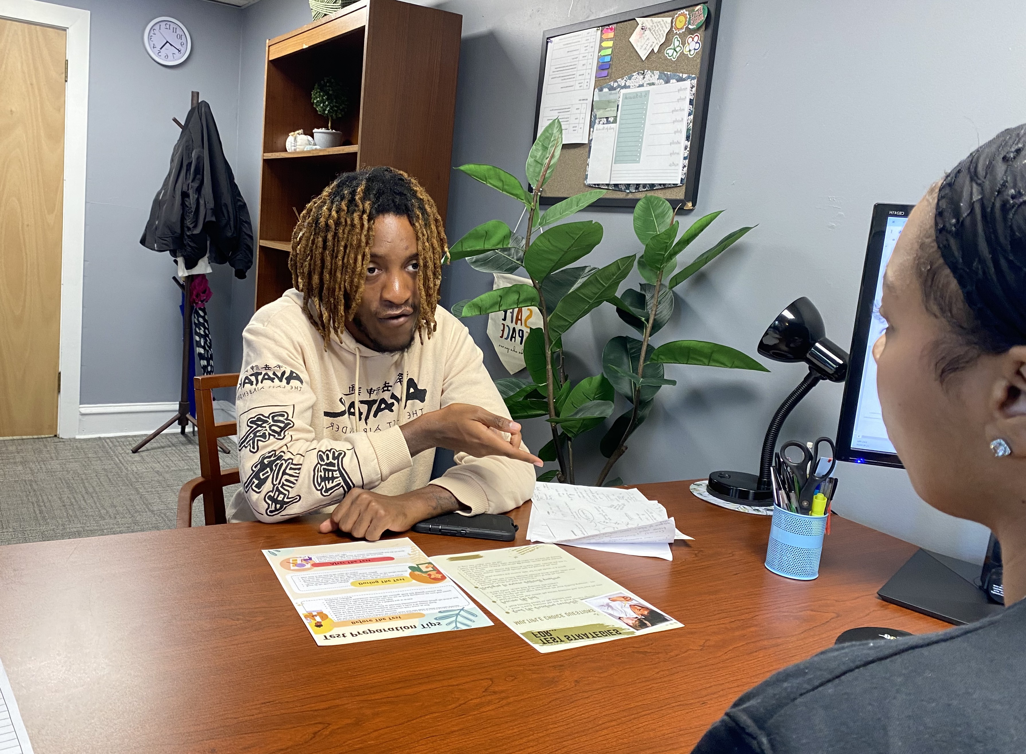 Male student talks with academic advisor in an office.