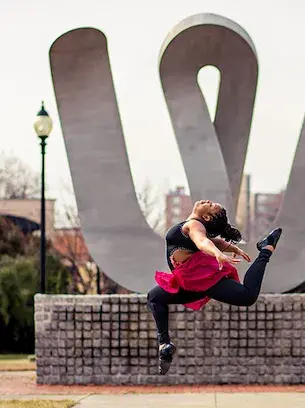 widener dance student mid-air in front of W statue