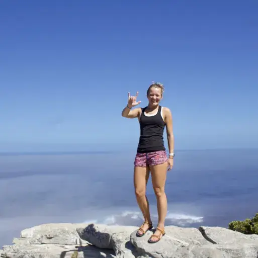 Hannah Berard stands on top of a mountain and signs "I love you"