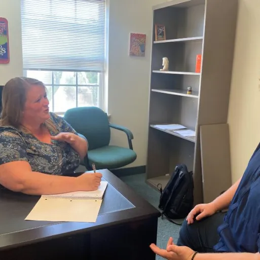 An online MSW student is seen sitting at a desk working with a client.