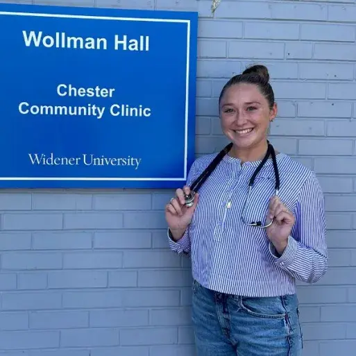 Taylor Wise poses in front of the Chester Community Clinic with her stethoscope draped around her neck.