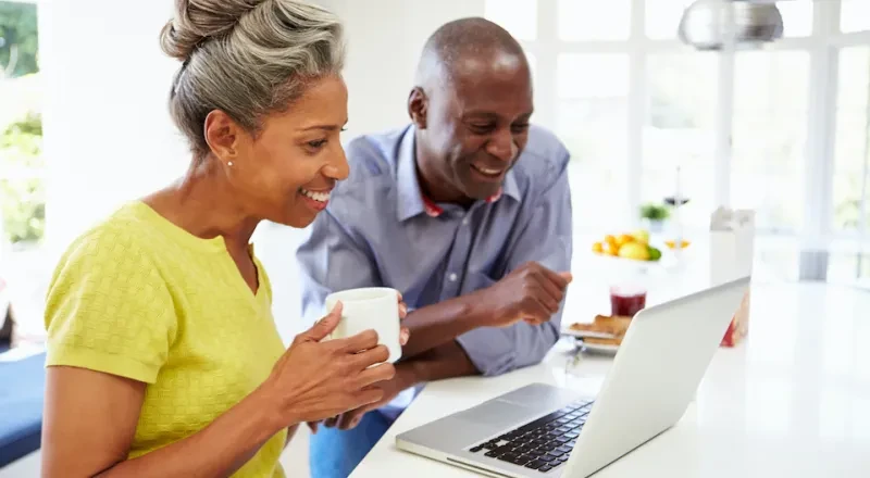 mature couple drinking coffee together at laptop