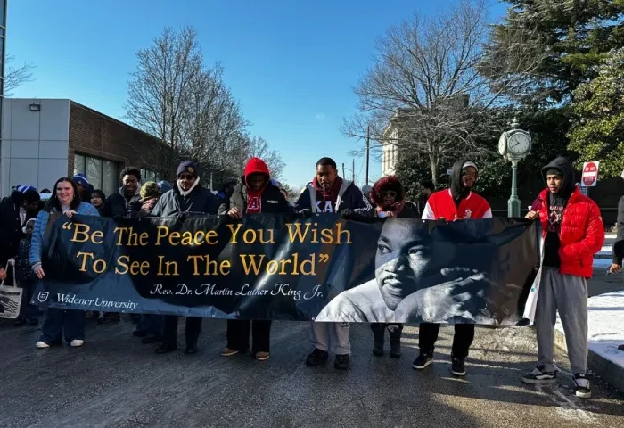 Students hold the MLK banner that reads "be the peace you wish to see in the world."