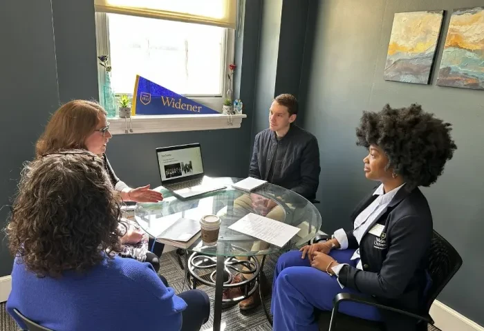 Three administrators and the (student) president for a day seated at a circular table in admissions.