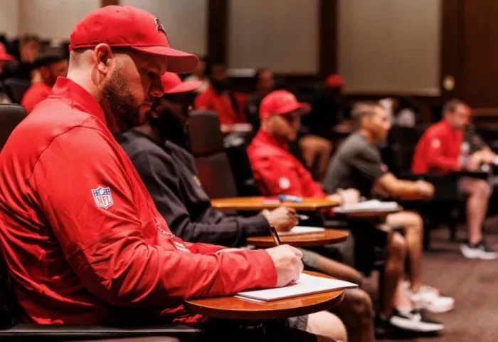 Mike Barainyak and other attendees sit at desks and take notes during a session