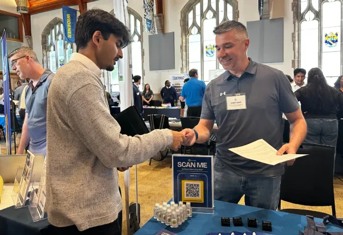 A student and employer exchange information at a career fair.