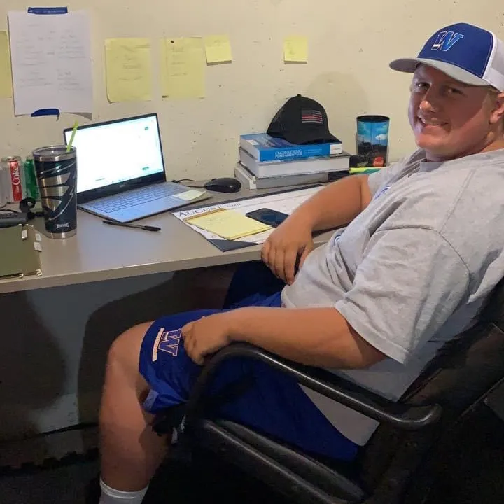 Student in Widener hat working at desk at home