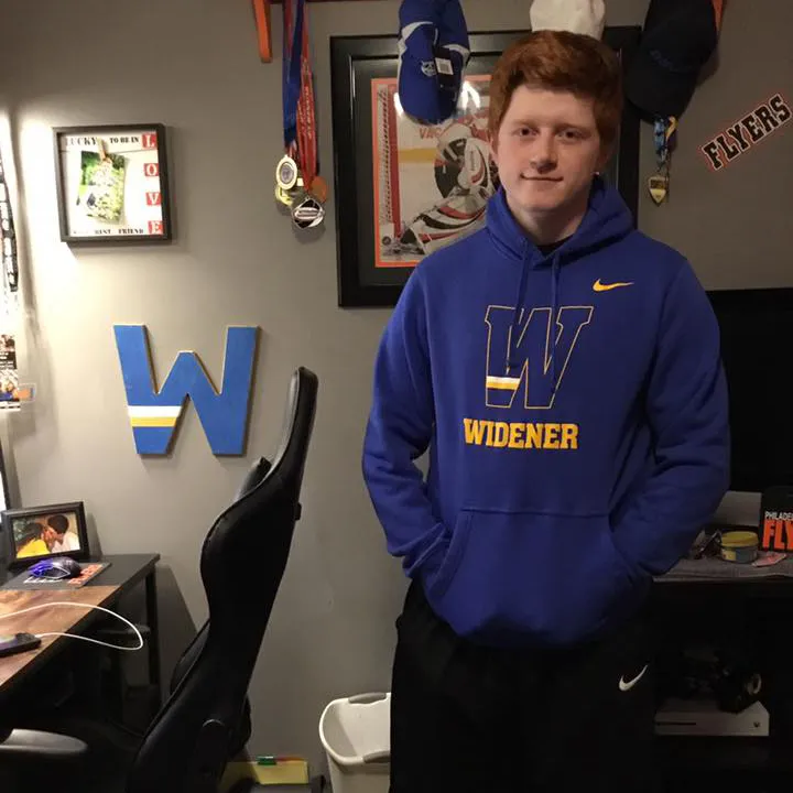 Student wearing Widener sweatshirt standing next to desk