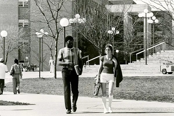 Black and white photo of two students walking on campus in 1978