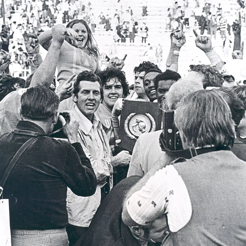 Black and white photo of football coach and students celebrating national championship
