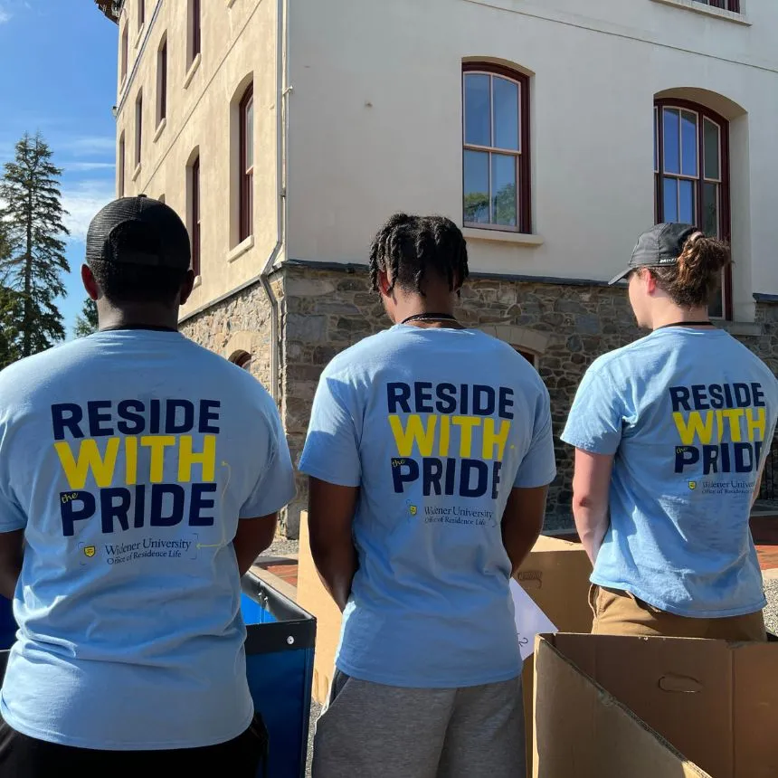 The back of move-in volunteer shirts read "Reside with Pride"