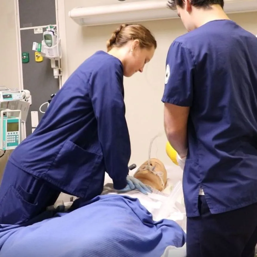 A female student performs compressions on a mannequin in the ICU unit.