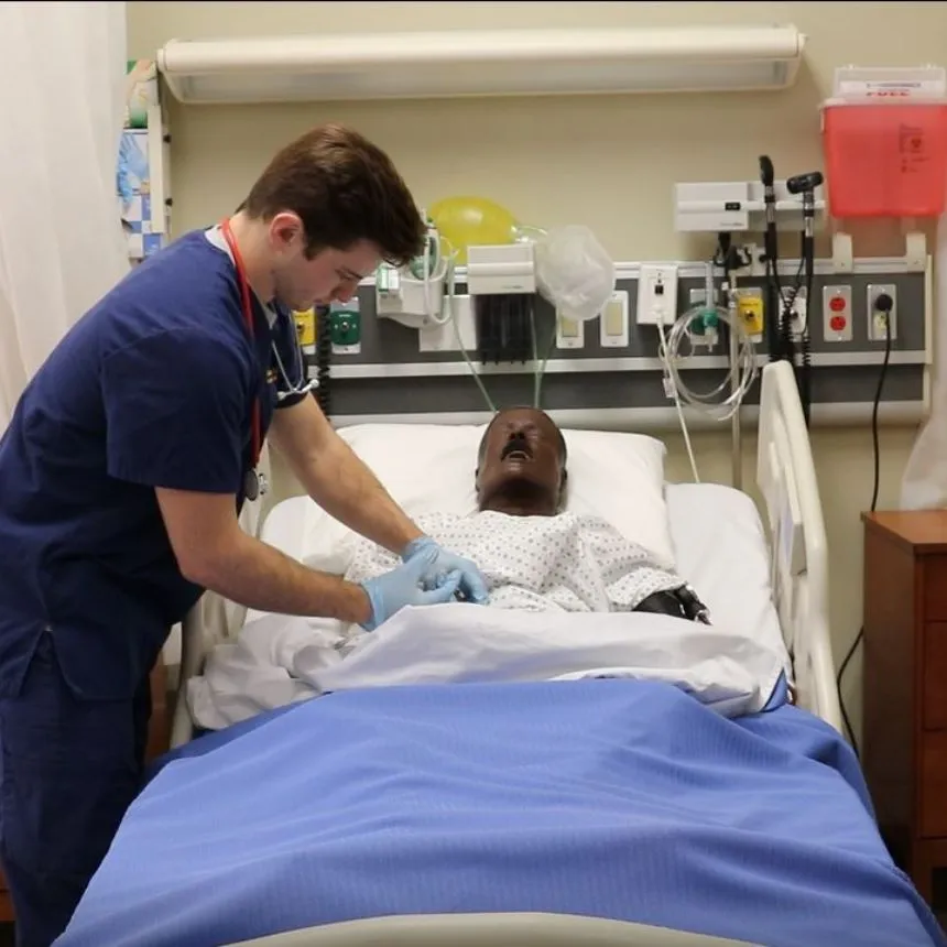 A male student injects medication into a mannequinn