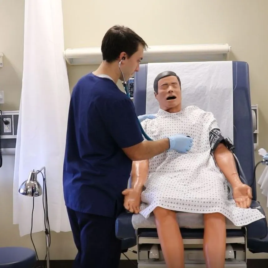 Male nursing student with mannequin in simulation lab.