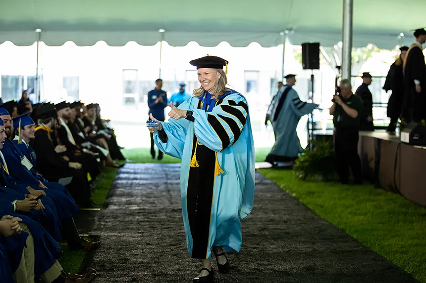 President Robertson walks past a row of graduates and gives them the thumbs up