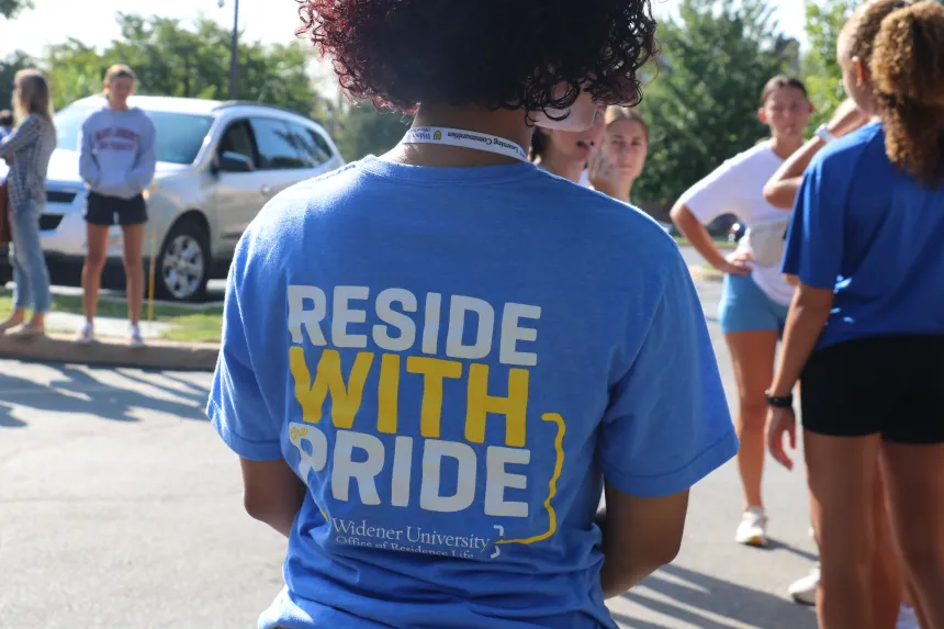 A student wears a light blue shirt that reads "Reside with pride" on the back