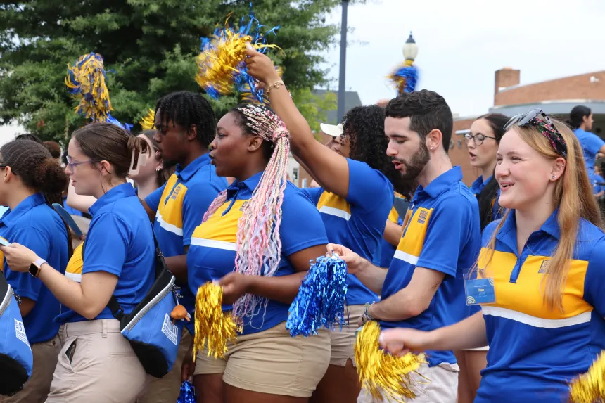 Student leaders with pom-poms cheer and sing