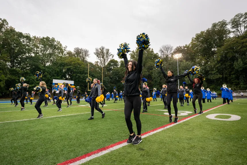 Cheerleaders jumping and cheering with pom poms in hand