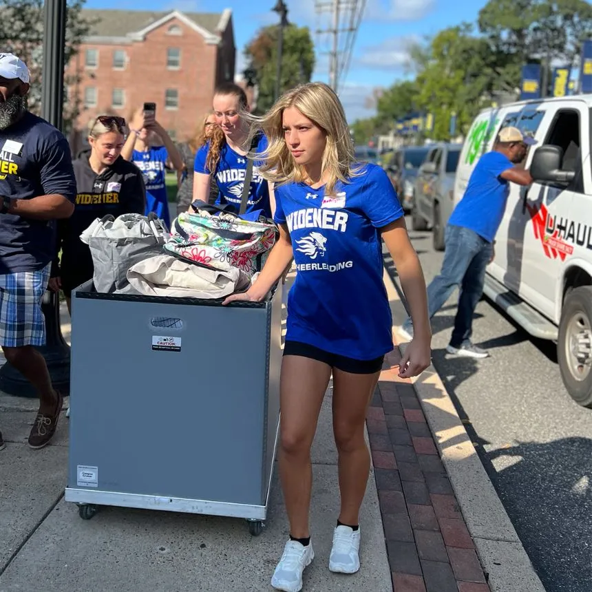 Members of the cheerleading team volunteer at move-in day and help roll bins to residence halls.