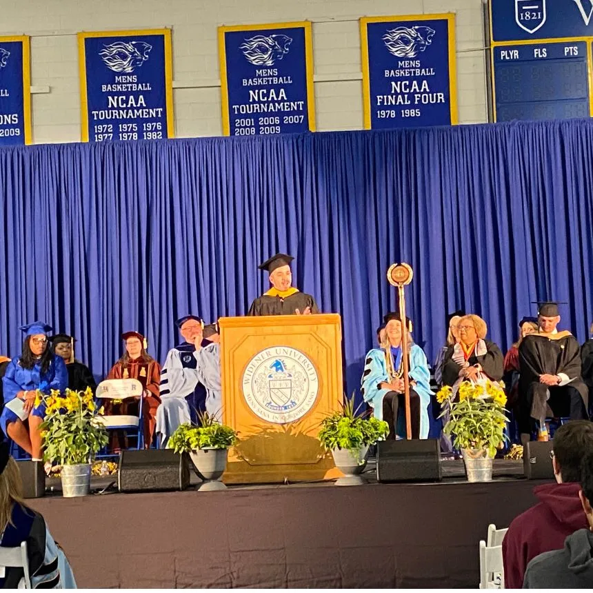 Prof. Mike Corcoran speaks at the podium during convocation.