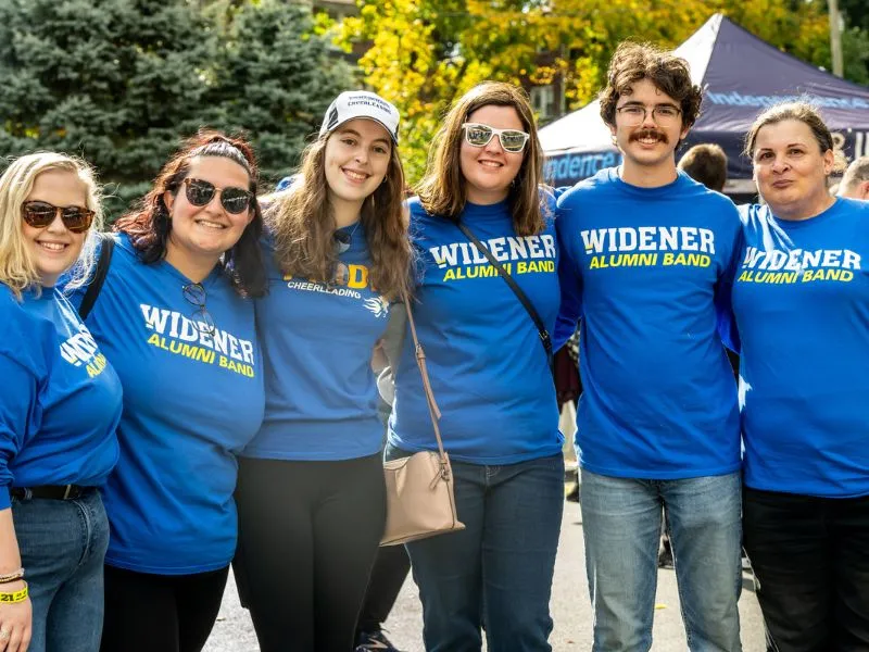 Alumni members of the Marching Band pose at the Homecoming Tailgate Village.
