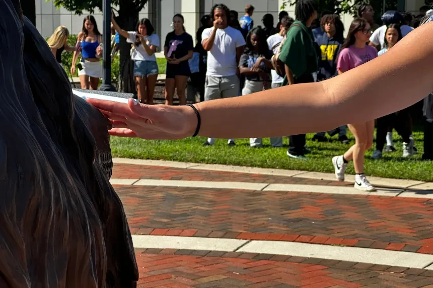 A student reaches out to rub the nose of the Chester lion statue for good luck.