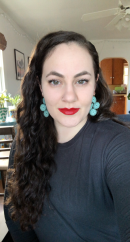 Jada Wittow wearing a dark shirt and blue earrings looking at the camera
