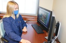 Female nursing student monitors patients remotely on a computer screen.