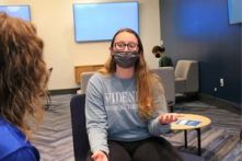 A female student sits in the University Center talking with a peer.