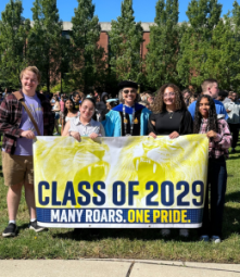 President Stacey Robertson and four students standing behind a class of 2029 banner