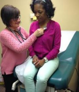 Professor Ellen Boyda with a stethoscope examining a female patient