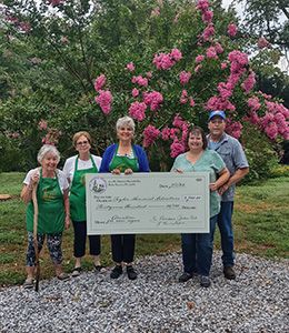 Five people stand with a giant check at the Taylor Arboretum