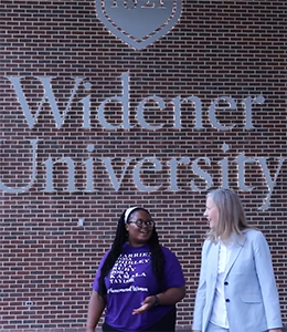 Student Taylor Easter walks with President Robertson in front of a Widener sign in the University Center