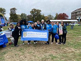 Students and faculty holding a Widener Social Work banner at the event