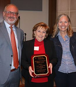 Vicki Brown holding award plaque alongside provost and president