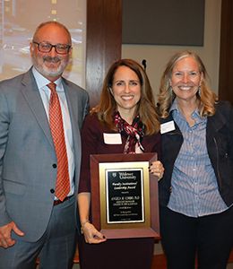 Angie Corbo holding award plaque standing alongside provost and president
