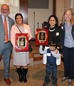 Professors Mazumder and Singh standing with their plaques alongside the provost and president